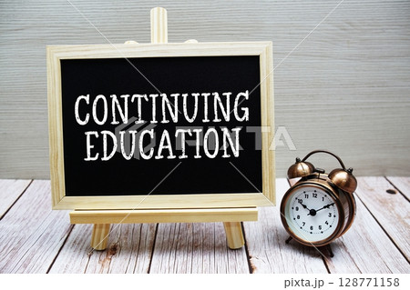 Continuing Education text written on chalkboard with alarm clock on wooden background Continuing Education text written on chalkboard with alarm clock on wooden background 128771158