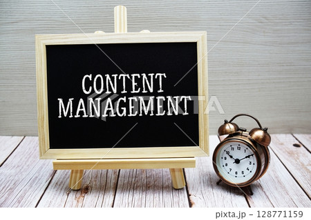 Content Management text written on chalkboard with alarm clock on wooden background 128771159