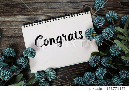 Congrats text with flowers decoration on wooden background Congrats text with flowers decoration on wooden background 128771173