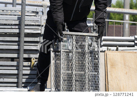 足場の組み立て 資材をトラックから降ろして準備する職人 足場の組み立て 資材をトラックから降ろして準備する職人 128771241