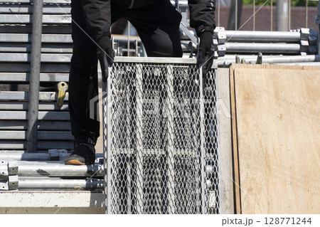 足場の組み立て 資材をトラックから降ろして準備する職人 足場の組み立て 資材をトラックから降ろして準備する職人 128771244