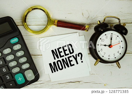 Need Money? text message on paper with magnifying glass, calculator and alarm clock on wooden background 128771385