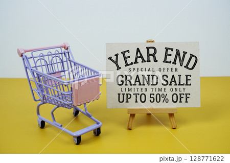 Year End Grand Sale 50% off text with mini trolley shopping cart on green background 128771622
