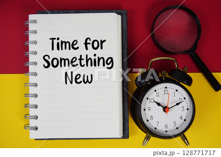 Time for Something New text written on notebook paper with magnifying glass and alarm clock 128771717