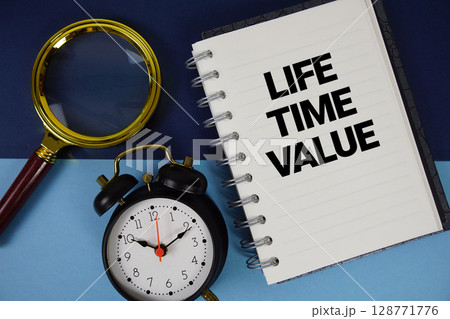 Life Time Value text written on notebook paper with magnifying glass and alarm clock 128771776