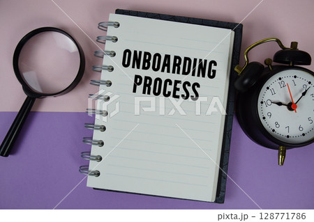 Onboarding Process text written on notebook paper with magnifying glass and alarm clock 128771786