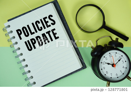 Policies Update text written on notebook paper with magnifying glass and alarm clock 128771801