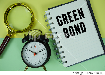 Green Bond text written on notebook paper with magnifying glass and alarm clock Green Bond text written on notebook paper with magnifying glass and alarm clock 128771804