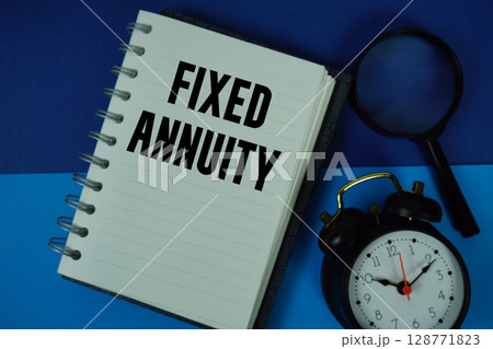 Fixed Annuity text written on notebook paper with magnifying glass and alarm clock Fixed Annuity text written on notebook paper with magnifying glass and alarm clock 128771823