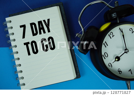 7 Day To go text written on notebook paper with alarm clock 128771827
