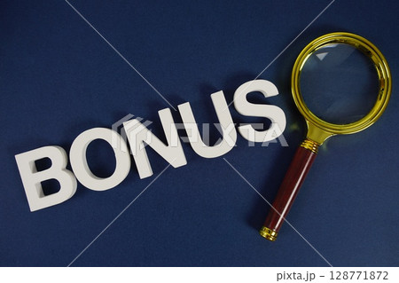 Bonus letters with magnifying glass flat lay on blue background 128771872