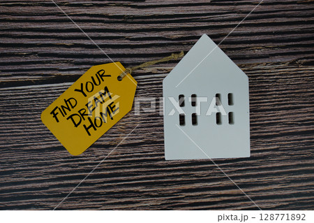Find Your Dream Home text on price tag with white house model flat lay on wooden background 128771892