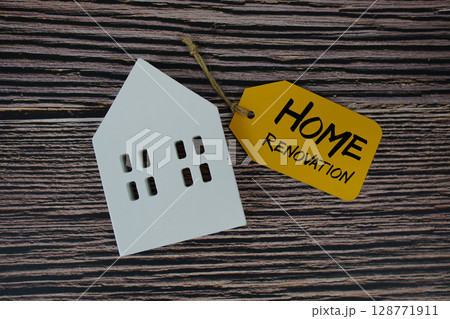 Home Renovation text on price tag with white house model flat lay on wooden background 128771911