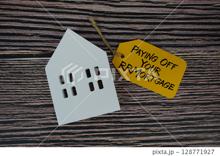 Paying Off Your Mortgage text on price tag with white house model flat lay on wooden background 128771927