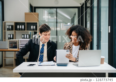 Businesswomen work and discuss their business plans. A Human employee explains and shows her colleague the results paper in modern office. Businesswomen work and discuss their business plans. A Human employee explains and shows her colleague the results paper in modern office. 128773745