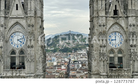 バシリカ教会の2つの時計塔と間から見えるEl Panecilloの丘（キト・エクアドル） 128773787