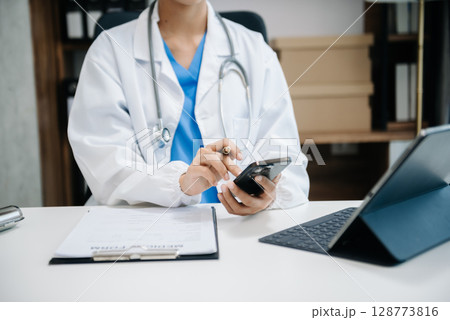 Medical technology concept. Doctor working with mobile phone and stethoscope and digital tablet laptop in office at hospital 128773816