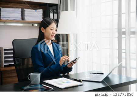 Woman accountant use Laptop and calculator to calculate the company's financial with icon banking on data network of finance and banking with business growth in office Woman accountant use Laptop and calculator to calculate the company's financial with icon banking on data network of finance and banking with business growth in office 128773856