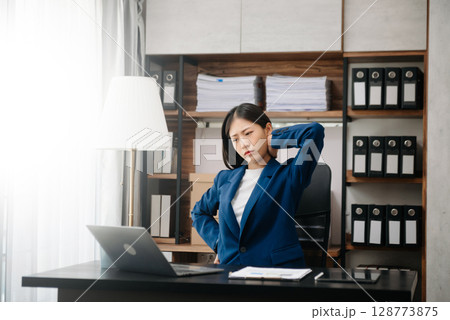 Woman feeling migraine head strain.Overworked businesswoman financier while working on laptop and tablet at office. 128773875