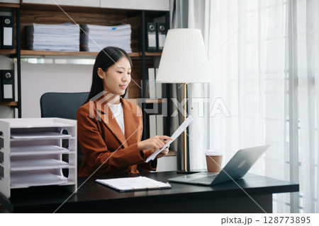 Business woman using tablet and laptop for doing math finance on an office desk, tax, report, accounting, statistics, and analytical research concept 128773895