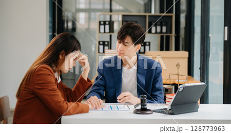 Business people compassionately holding hands and discussing contract papers with laptop and tabletat office 128773963