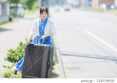 笑顔でスーツケースを持つ女性 笑顔でスーツケースを持つ女性 128774019