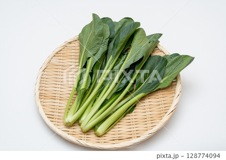 新鮮な小松菜をざるに盛った白背景の写真 128774094