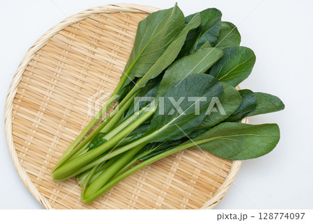 新鮮な小松菜をざるに盛った白背景の写真 128774097