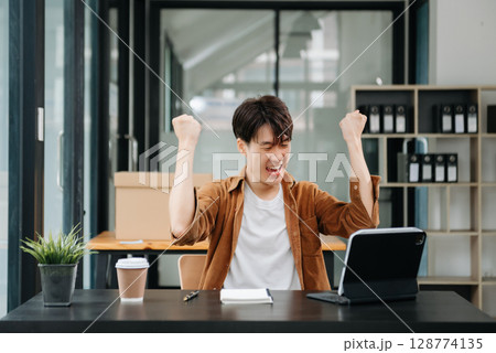 Asian businessman are delighted and happy with the work they do on their tablet, laptop and taking notes at the office. 128774135