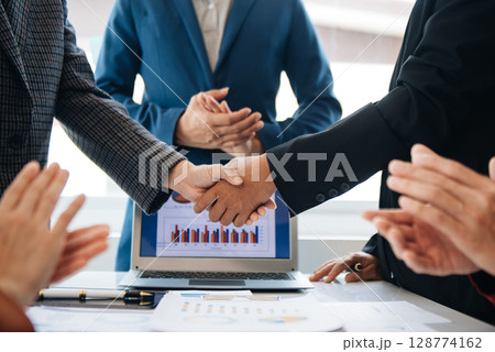 business people shaking hands during a meeting in modern office business people shaking hands during a meeting in modern office 128774162