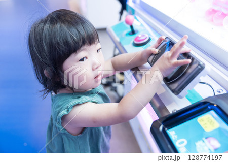 ゲームセンターのUFOキャッチャーで遊ぶ女の子の幼児 ゲームセンターのUFOキャッチャーで遊ぶ女の子の幼児 128774197