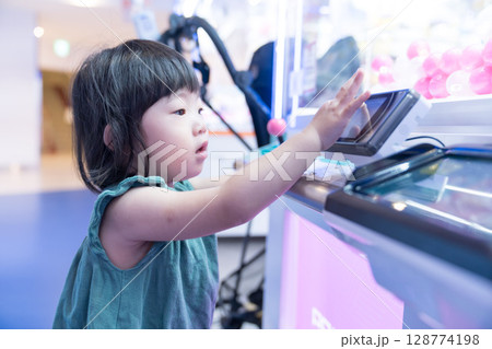 ゲームセンターのUFOキャッチャーで遊ぶ女の子の幼児 128774198