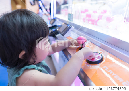 ゲームセンターのUFOキャッチャーで遊ぶ女の子の幼児 ゲームセンターのUFOキャッチャーで遊ぶ女の子の幼児 128774206