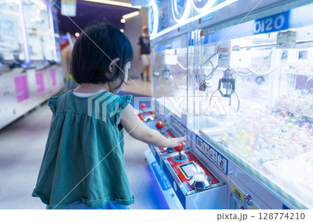 ゲームセンターのUFOキャッチャーで遊ぶ女の子の幼児 ゲームセンターのUFOキャッチャーで遊ぶ女の子の幼児 128774210
