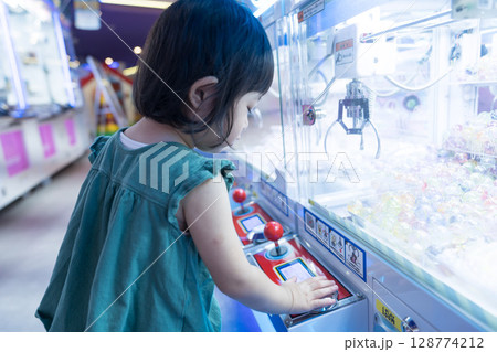 ゲームセンターのUFOキャッチャーで遊ぶ女の子の幼児 ゲームセンターのUFOキャッチャーで遊ぶ女の子の幼児 128774212