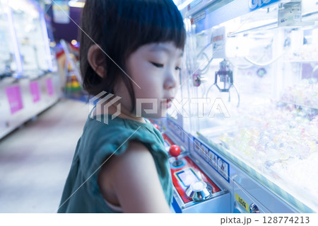 ゲームセンターのUFOキャッチャーで遊ぶ女の子の幼児 ゲームセンターのUFOキャッチャーで遊ぶ女の子の幼児 128774213