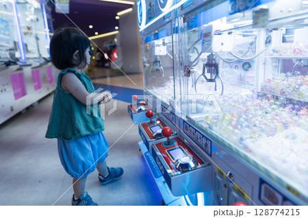 ゲームセンターのUFOキャッチャーで遊ぶ女の子の幼児 128774215