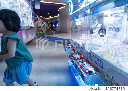 ゲームセンターのUFOキャッチャーで遊ぶ女の子の幼児 ゲームセンターのUFOキャッチャーで遊ぶ女の子の幼児 128774216