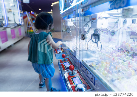 ゲームセンターのUFOキャッチャーで遊ぶ女の子の幼児 128774220