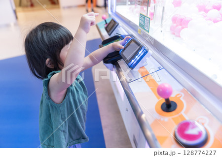 ゲームセンターのUFOキャッチャーで遊ぶ女の子の幼児 128774227
