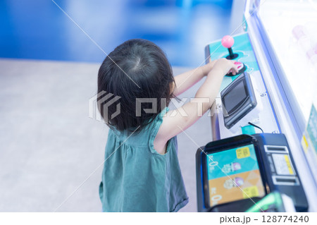 ゲームセンターのUFOキャッチャーで遊ぶ女の子の幼児 ゲームセンターのUFOキャッチャーで遊ぶ女の子の幼児 128774240