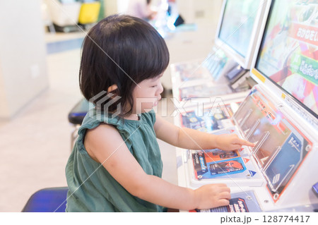 ゲームセンターのゲームで遊ぶ女の子の幼児 128774417