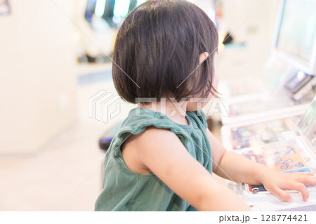 ゲームセンターのゲームで遊ぶ女の子の幼児 128774421
