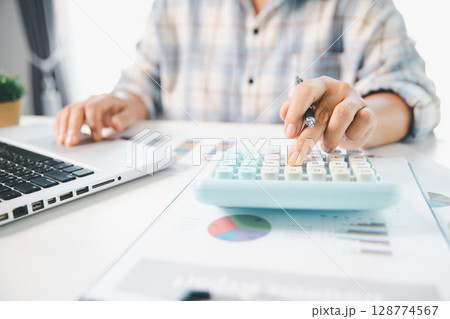 Accountant working on desk using calculator for calculate finance report in office. business finance, calculate tax by organizing financial documents, tracking income investment, accounting by hand. Accountant working on desk using calculator for calculate finance report in office. business finance, calculate tax by organizing financial documents, tracking income investment, accounting by hand. 128774567