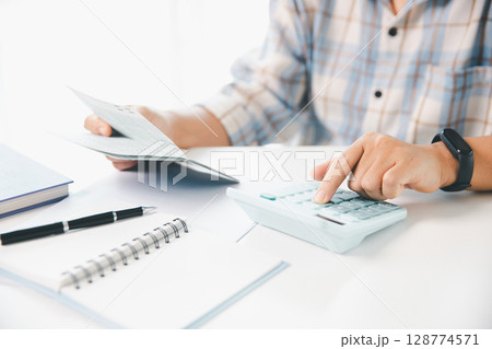 Business hands holding saving account passbook with calculator, account and saving concept. finance effectively, calculate income, track each bill and payment, accounting for bank statements and tax. 128774571