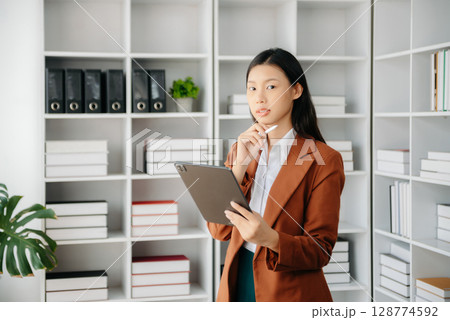 Beautiful Asian business woman typing laptop and tablet Placed at the table at the office Beautiful Asian business woman typing laptop and tablet Placed at the table at the office 128774592