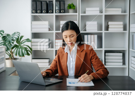 Beautiful Asian business woman typing laptop and tablet Placed at the table at the office 128774837