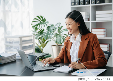 Beautiful Asian business woman typing laptop and tablet Placed at the table at the office Beautiful Asian business woman typing laptop and tablet Placed at the table at the office 128774843