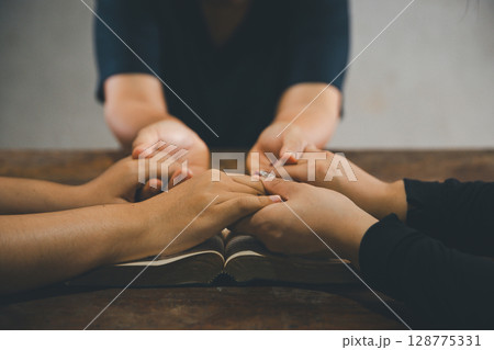 Praying religion, worship and group of people pray to God, Family, holding hands and prayer in home for love, support and faith or hope in house. holy spirit or Jesus for peace or spiritual praise. 128775331