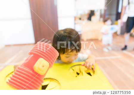 保育園のモグラ叩きで遊ぶ女の子の幼児 保育園のモグラ叩きで遊ぶ女の子の幼児 128775350